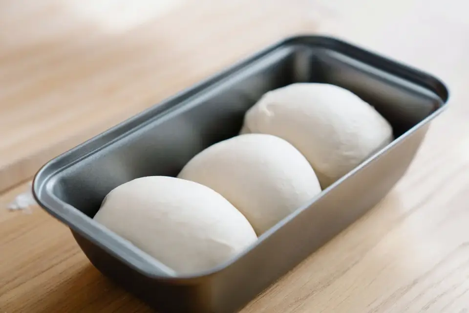 A bowl of raw bread dough rising on a kitchen counter