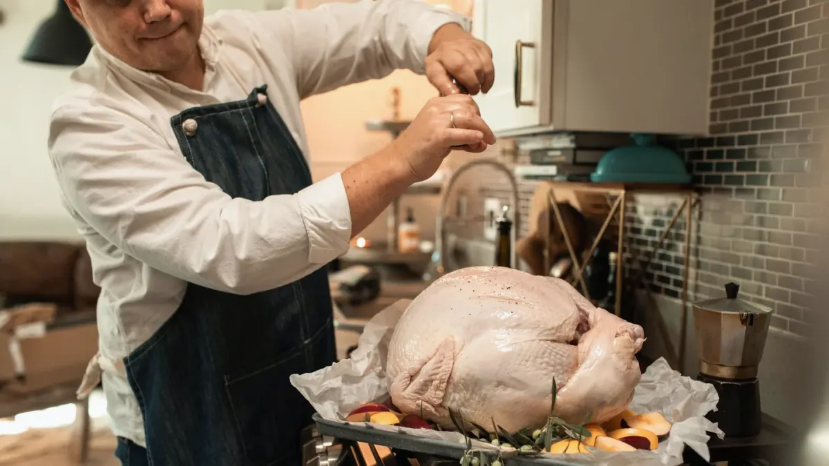 A carved turkey resting on a kitchen counter while a dog waits nearby