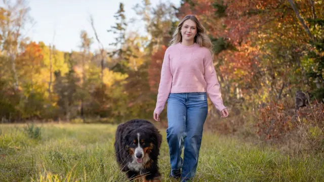 A dog and its owner walking together on a wooded trail