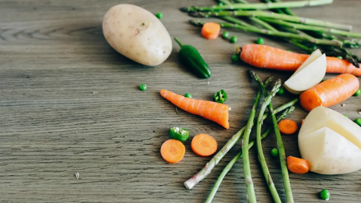 A dog sniffing carrot pieces cut into small sticks on a kitchen floor