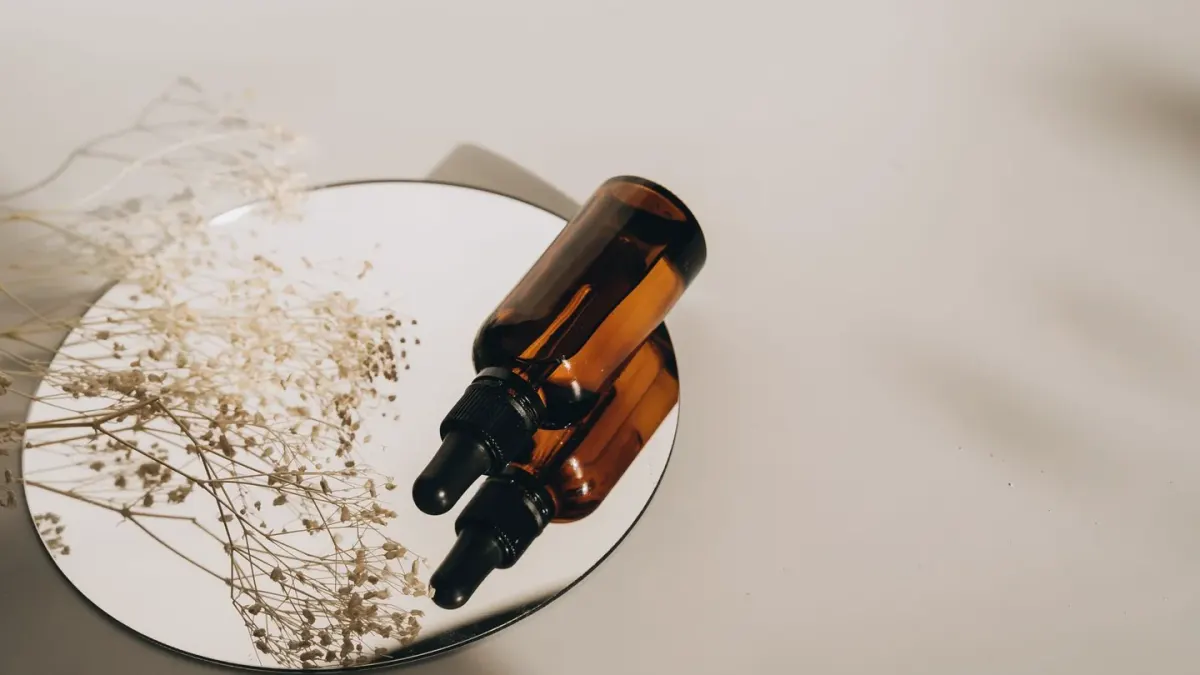 A dropper bottle of oil being measured next to a dog's paw