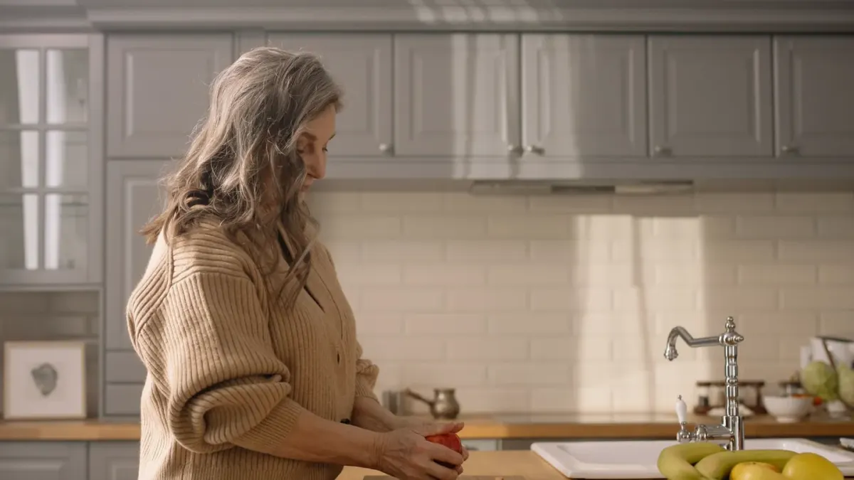 A senior dog eating from a stainless steel bowl in a home kitchen