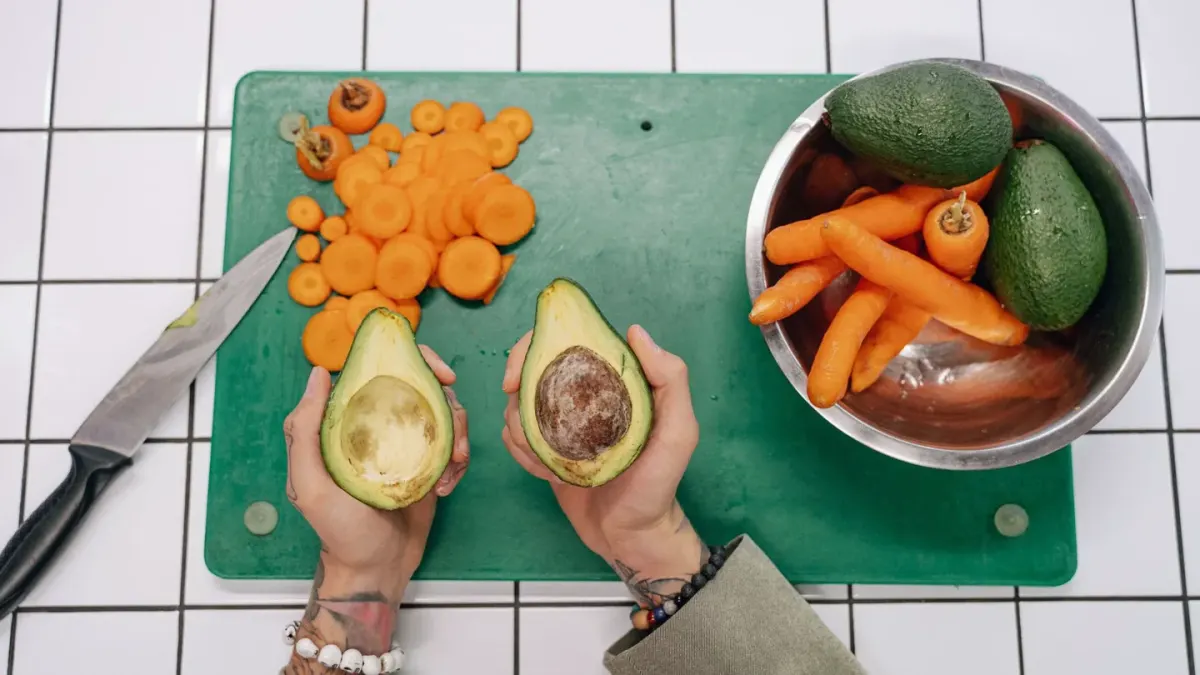 A sliced avocado on a cutting board while a dog watches nearby