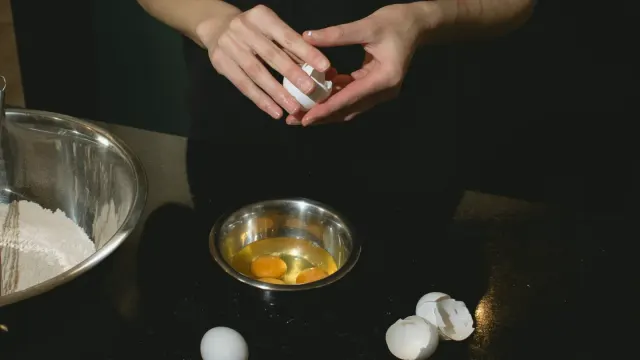 A small plate of plain scrambled eggs sitting next to a dog's stainless steel food bowl on a kitchen counter