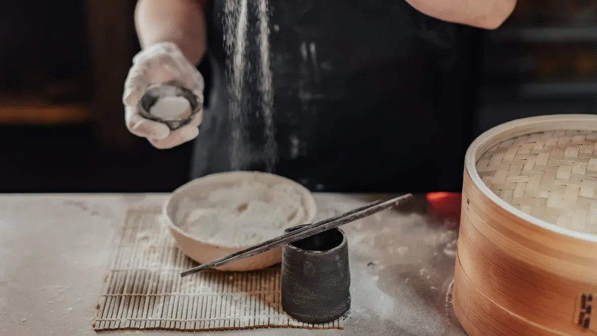 An owner spooning a supplement powder over a senior dog's food bowl in a home kitchen
