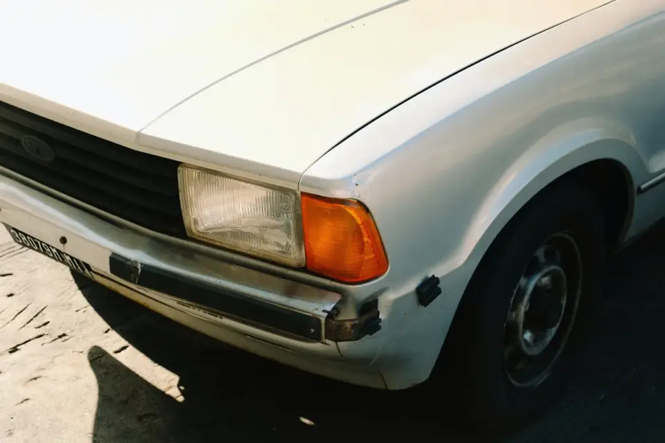 Folded travel ramp resting against the bumper of a parked car