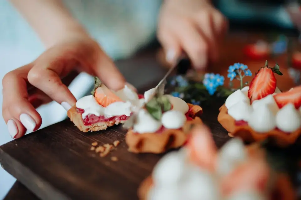 Fresh strawberries being sliced into small pieces on a cutting board