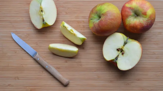 Sliced apple pieces on a cutting board beside an attentive dog